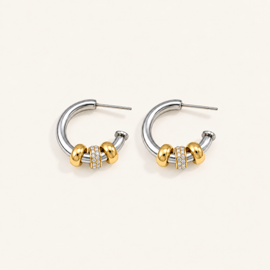 Pair of waterproof silver hoop earrings with gold beads and a crystal pavé band on a pale beige background.