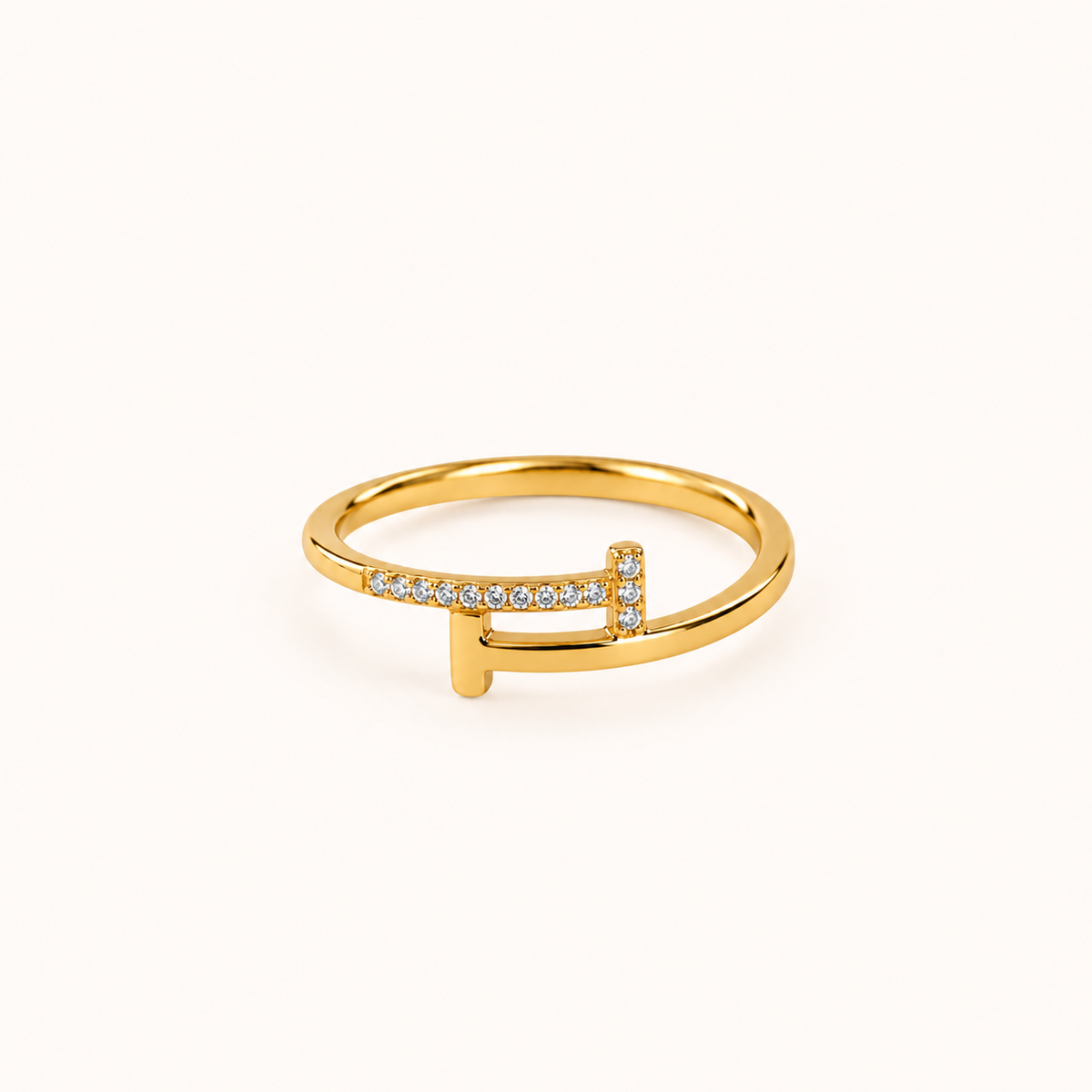 Cleo waterproof gold ring featuring a modern open geometric design with sparkling clear zirconia stones and a polished gold finish, photographed on a soft ivory beige background.