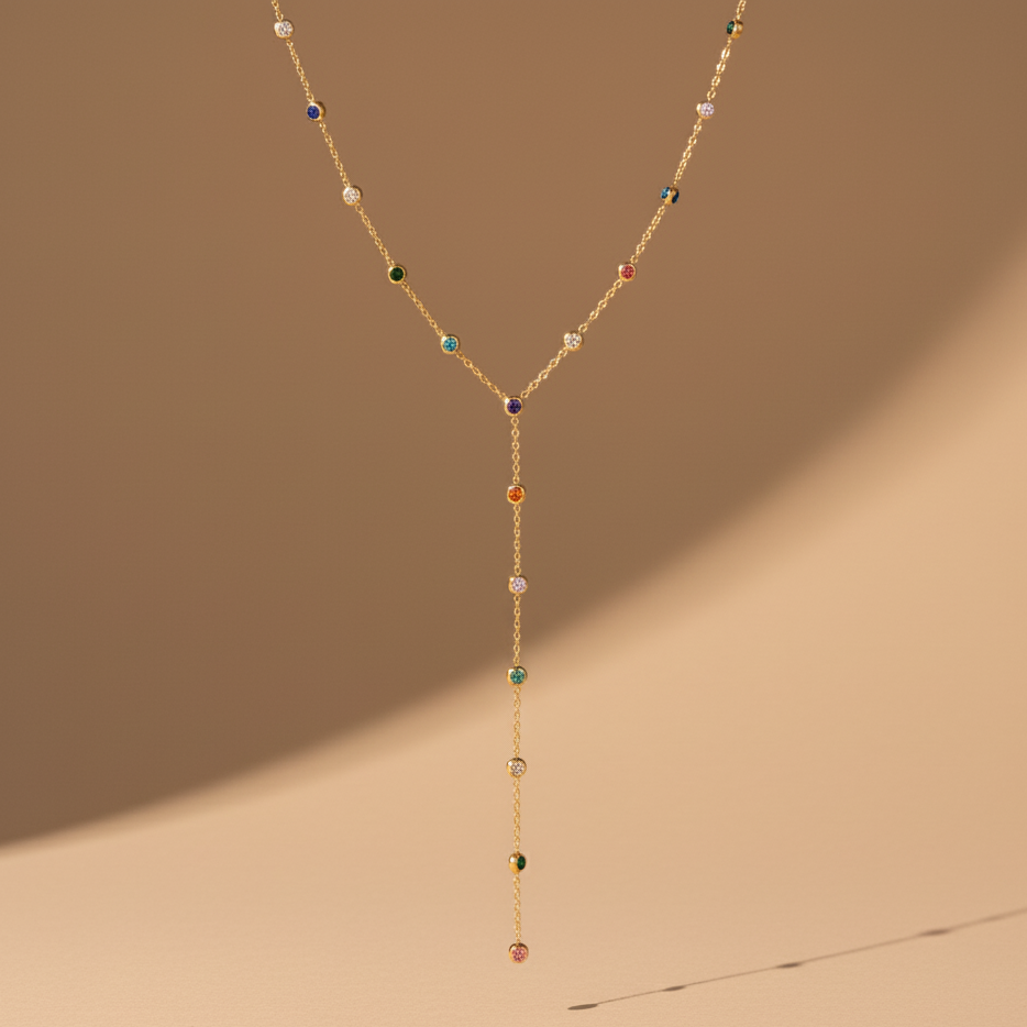 Delicate gold necklace with colorful beads on a beige background