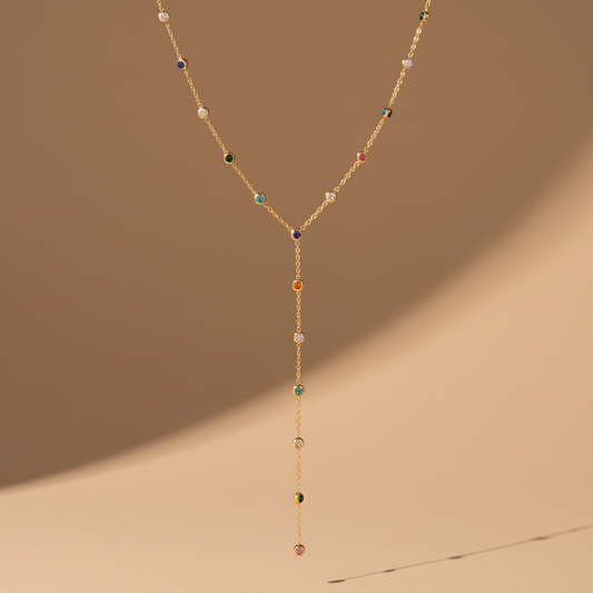 Delicate gold necklace with colorful beads on a beige background