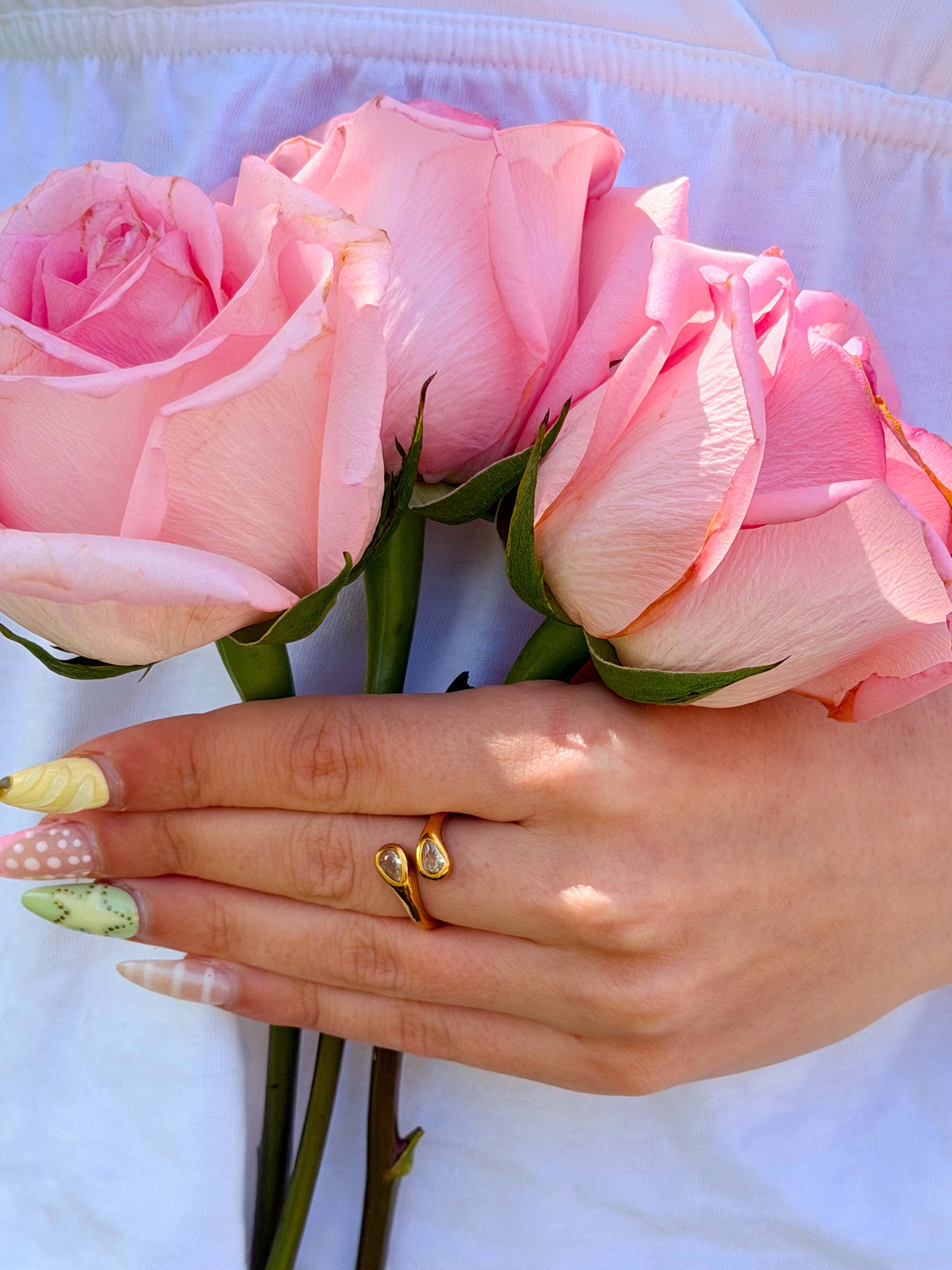Hand holding pink roses with a gold ring on a white background