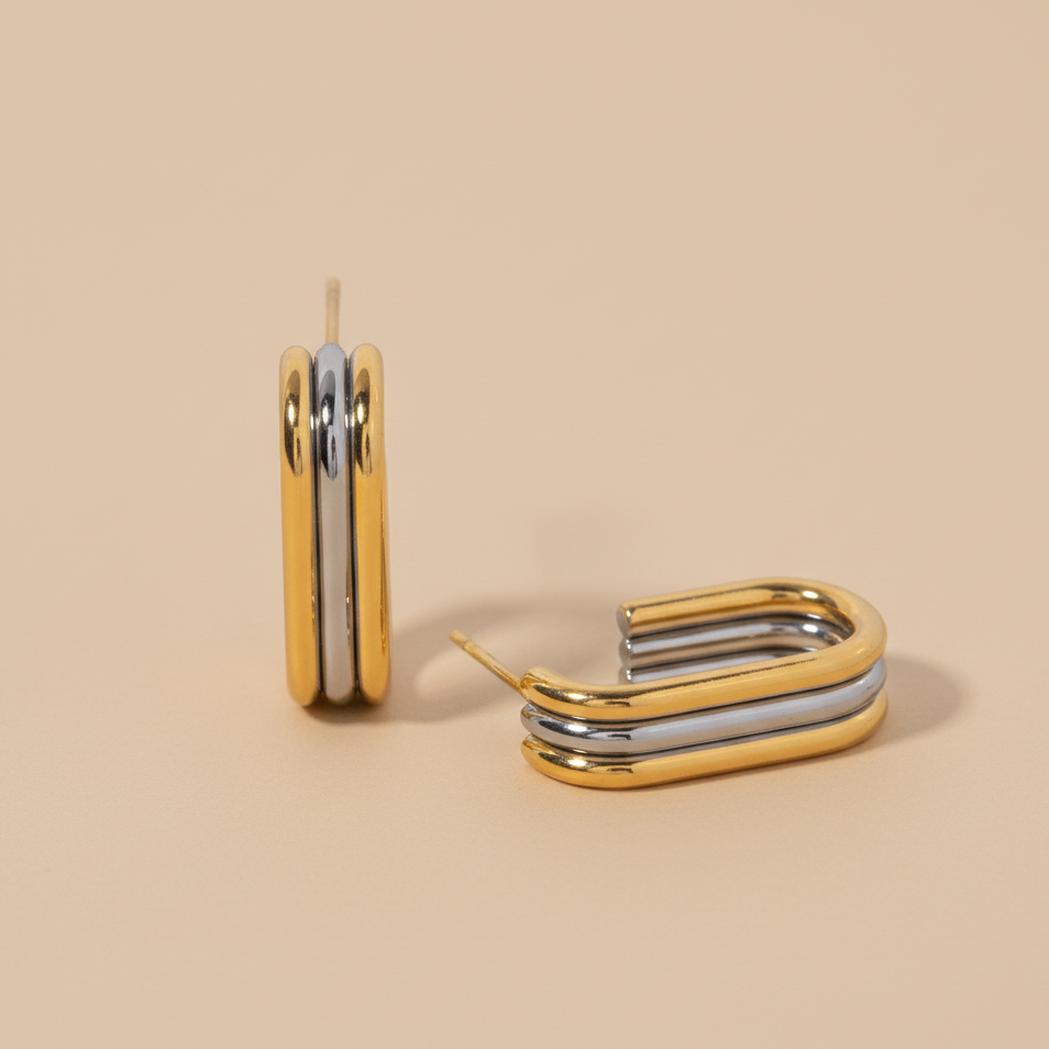 Two-tone gold and silver hoop earrings on a neutral background