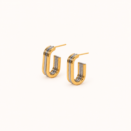 Two-tone gold and silver geometric hoop earrings on a neutral background
