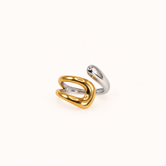 A two-tone abstract open ring in polished gold and silver, photographed on a clean off-white background.