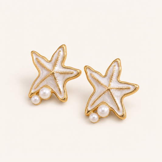 A pair of waterproof gold starfish stud earrings with white faux-pearl inlay and small white pearl accents, shown on a clean off-white background. 